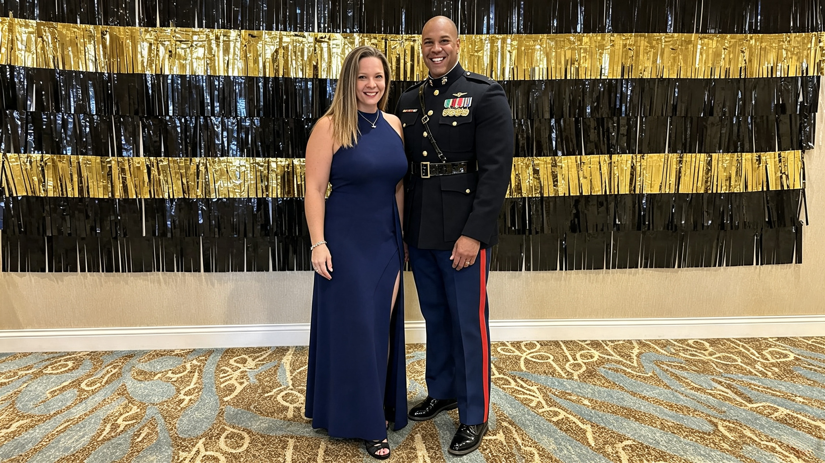 Woman standing with husband in military uniform wearing a navy halter formal gown