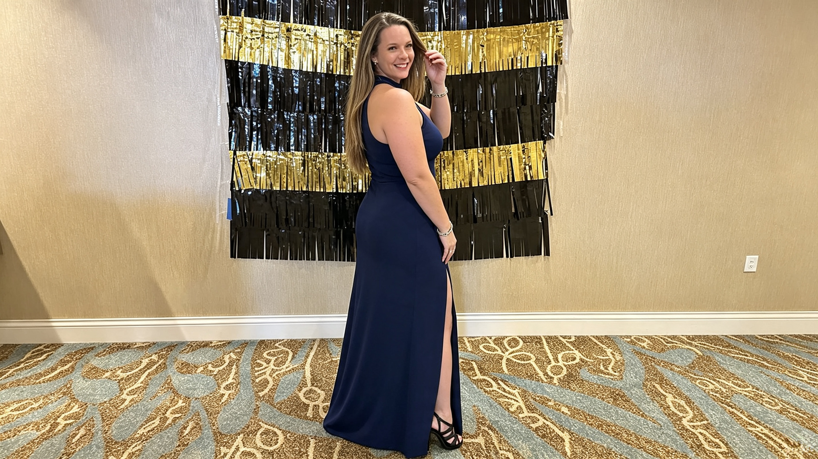 Woman confidently posing in a navy halter gown with high slit at a formal event