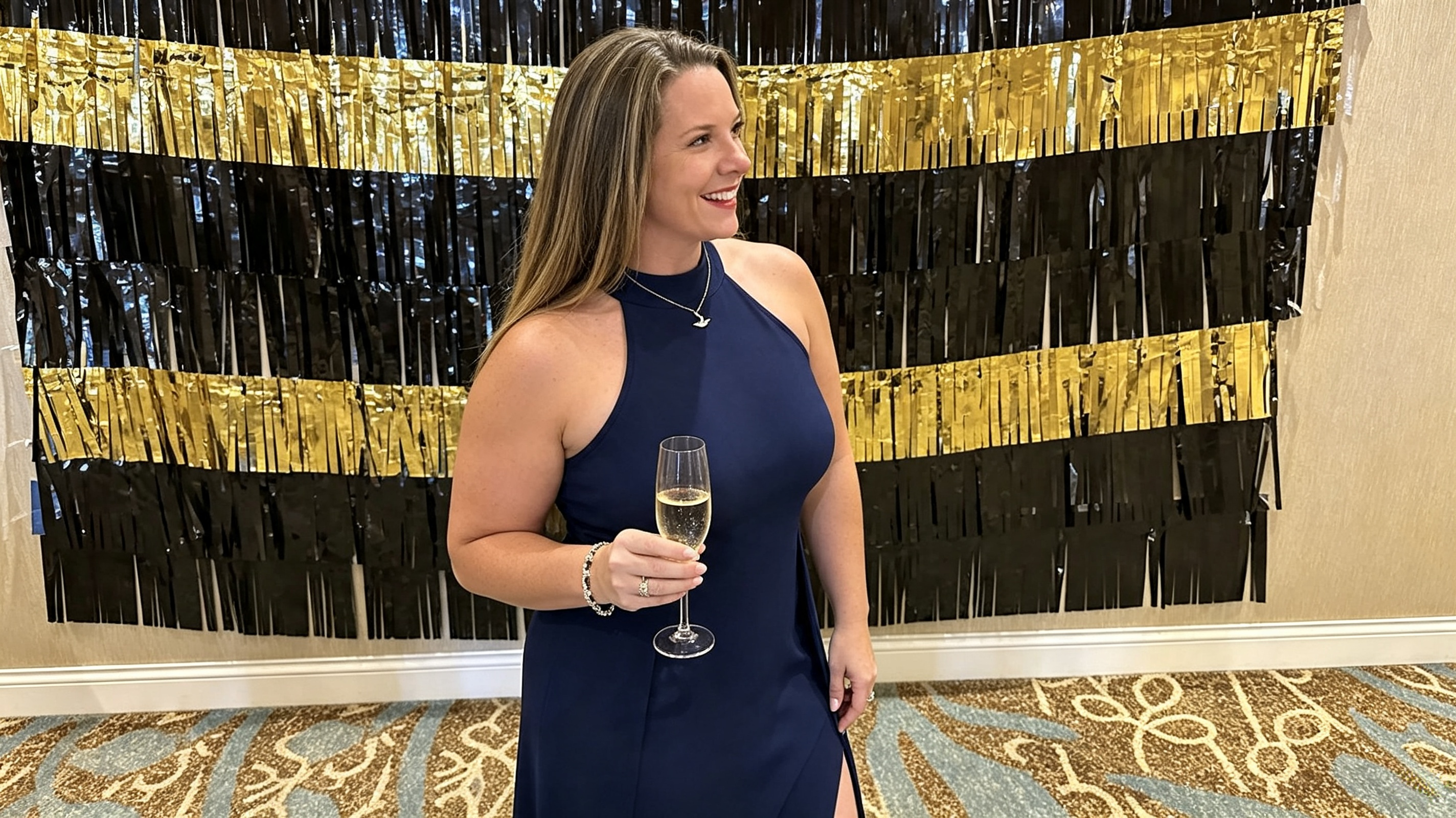 Woman holding a drink while wearing a navy high slit formal maxi dress